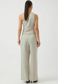 Ljust grå, skräddarsydd jumpsuit med asymmetrisk halsringning och vida byxor. Slät tyg med minimalistisk design och inga synliga dekorationer.
