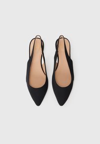 Slingbacks pretos com bico apontado, tecido liso, laterais recortadas e uma palmilha bege com uma marcação discreta.