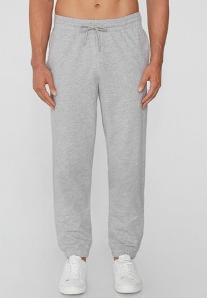 Gray cotton sweatpants with elastic cuffs and a drawstring waistband, paired with white sneakers. Soft texture, relaxed fit.