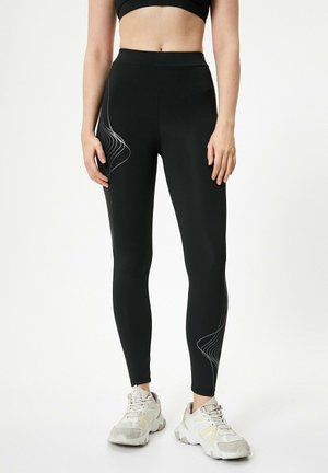 Black leggings with a high waistband, featuring white wave-patterned lines on the side and a smooth, stretchy matte finish.