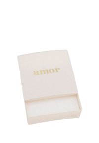 En fyrkantig, off-white låda med rundad topp. Ordet "amor" är präglat i guld på locket. Inuti är den klädd med ett mjukt, beige material.