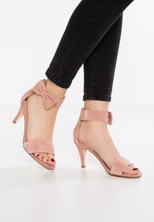 Roze suède hoge hakken sandalen met een open teen, enkelbandje en strikdetail aan de achterkant. Gladde textuur, slanke hak.