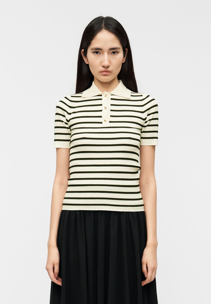 Ριγέ πόλο μπλουζάκι με κοντά μανίκια σε εκρού και σκούρο πράσινο, με ριμπ υφή, διαθέτει γιακά και τρία διακοσμητικά κουμπιά.