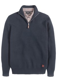 Marineblaues Viertelreißverschluss-Pullover, über einem karierten Button-Up-Hemd getragen, mit einem Lederreißverschlussgriff und kleinem Leder-Logo-Patch.