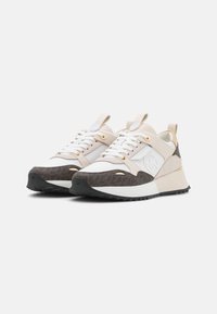 Sneakers met een mix van wit en beige stof, een onderste gedeelte met een bruine patroon, gouden accenten en een gestructureerde zwarte rubberen zool.