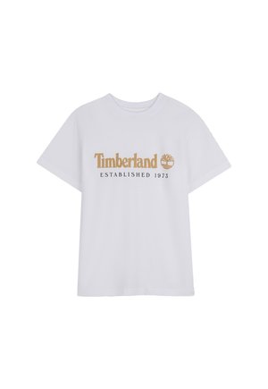 Maglietta bianca a maniche corte con logo "Timberland" marrone e emblema ad albero sopra il testo "ESTABLISHED 1973" sulla parte anteriore.