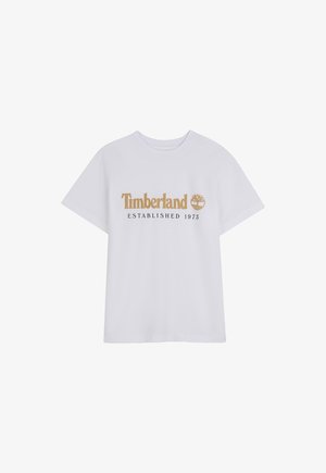 Maglietta bianca a maniche corte con logo "Timberland" marrone e emblema ad albero sopra il testo "ESTABLISHED 1973" sulla parte anteriore.