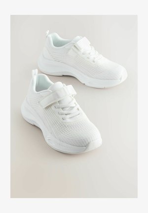 Valged spordijalatsid, millel on tekstuuriga võrkkangas, pitsid ja Velcro rihmad, pehmendatud krae ning paks kummist tall.