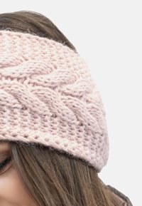 Stickad huvudband i mjuk rosa, med en kabelmönster. Tillverkat av texturerad garn, har det en bred, elastisk design för bekväm användning.
