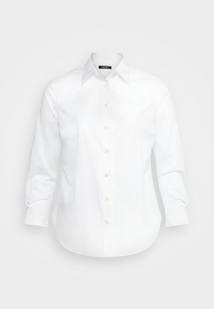 Camisa blanca de botón con cuello puntiagudo, mangas largas y dobladillo curvado. Fabricada con una tela suave y pequeños detalles de costura sutiles.