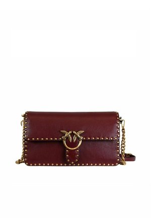 Pochette in pelle rosso scuro con borchie dorate, tracolla a catena dorata e chiusura circolare dorata con due uccelli che si fronteggiano.