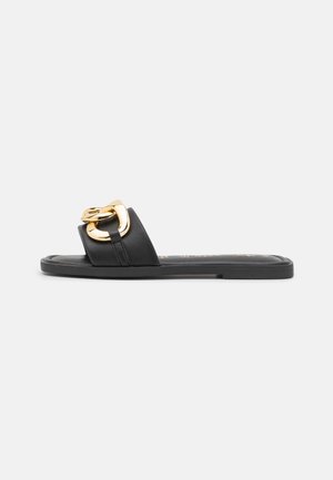 Sorte lædersandal med brede stropper og iøjnefaldende guldhardwaredetalje. Glat overflade med flad sål og minimalistisk design.