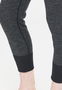 Graue Sportleggings mit glatter Textur, tailliertem Schnitt und schwarzen Knöchelbündchen mit kontrastierenden Nähten. Ideal für Sportbekleidung.