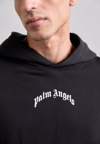 Hanorac negru din material moale, cu un logo alb care spune „palm Angels” în font îndrăzneț, gotic, pe piept. Design simplu și casual.