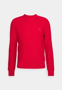 Suéter rojo de manga larga, con puños y cuello acanalados. Presenta un pequeño logo texturizado en el pecho. Fabricado en material de punto.