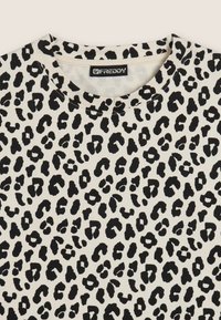 T-shirt con stampa leopardata su sfondo crema, caratterizzato da macchie nere, scollatura rotonda e una texture di tessuto morbido. Etichetta del brand visibile.