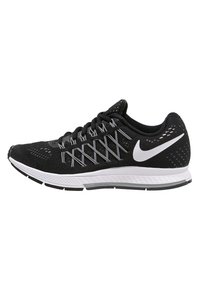 Baskets de course noires avec une tige en mesh, semelle blanche et lacets gris. Présente un logo Nike bien visible et des motifs texturés sur la tige.