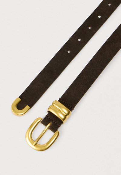 Καφέ ζώνη από σουέτ με μεταλλική αγκράφα χρυσού χρώματος και διακοσμητικά στοιχεία, με λεία υφή και πολλαπλές οπές για ρυθμιζόμενο μέγεθος.