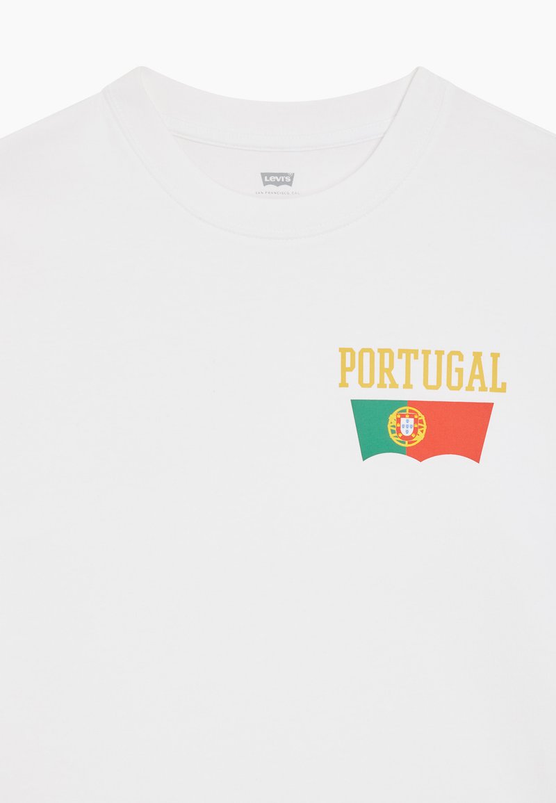 Άσπρο t-shirt Levi's με κίτρινο κείμενο "PORTUGAL" πάνω από μια στυλιζαρισμένη σημαία με πράσινο, κόκκινο και το εθνικό έμβλημα της Πορτογαλίας.
