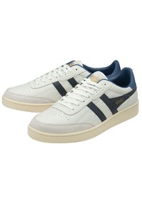 Witte leren sneakers met marineblauwe accenten en strepen. Textuur bovenwerk met perforaties en een crèmekleurige rubberen zool. Gola-logo aan de zijkant.