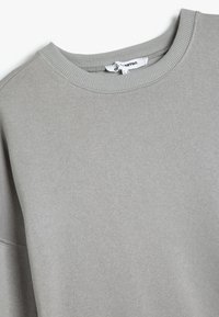 Felpa grigia chiara con collo a girocotolo a costine. Tessuto morbido e testurizzato; vestibilità comoda; etichetta visibile sul collo. Design semplice, senza abbellimenti.