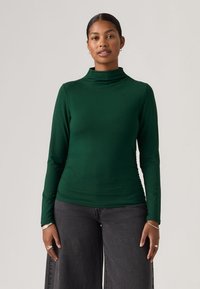 Groen nauwsluitend coltrui-top met lange mouwen, gemaakt van gladde stof en met een aansluitende pasvorm. Heeft een hoge hals en geplooide details aan de zijkant.