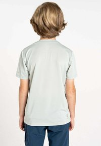 Helle graue Kurzarm-T-Shirt mit Rundhalsausschnitt, strukturiertem Stoff und kleinem Logodetail auf der Rückseite. Kombiniert mit dunkelblauen Hosen.