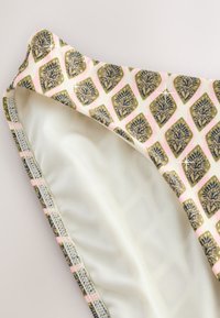 Primo piano del fondo bikini con motivo a diamante rosa e oro e dettagli floreali neri su fodera in tessuto bianco.