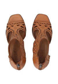 Kožené sandály v tan barvě s perforovaným designem a trojúhelníkovými výřezy, které mají zip na kotníku. Vnitřek je hladký, s plochou podrážkou.