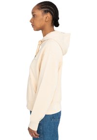 Beige hooded sweatshirt with a kangaroo pocket, drawstring, and ribbed cuffs. Fabric appears soft, with a relaxed fit and no visible patterns.