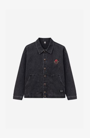 Svart denimjacka med knappar framtill, två stora fickor, ett litet rött trädemblem på vänstra bröstet och en "Kaotiko Society"-etikett nära botten.