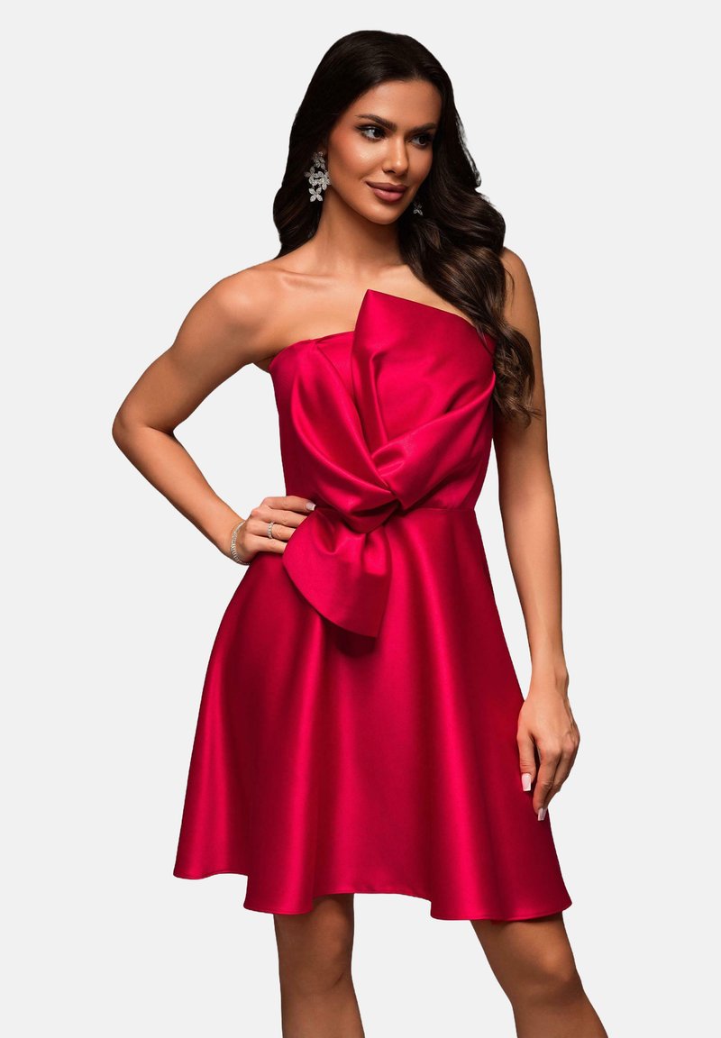 Robe sans bretelles, longueur genou, en satin rouge vif avec un grand nœud à la taille, présentant une texture lisse et brillante et une jupe évasée.