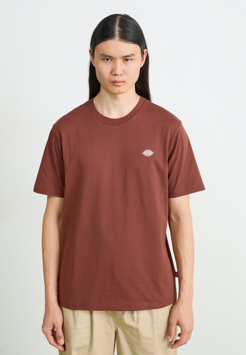 Bruine katoenen T-shirt met ronde hals, korte mouwen en een klein logo op de borst. Soepele textuur, relaxte pasvorm.