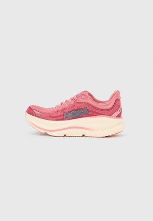 Pink running shoe with a textured upper, featuring a blue logo on the side and a thick cream-colored midsole. Streamlined design with laces.