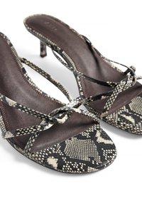 Čierne a béžové sandále s hadím vzorom, so štíhlymi krížovými popruhmi a nízkym opätkom. Mäkká kožená textúra s hladkým vnútorným povrchom.