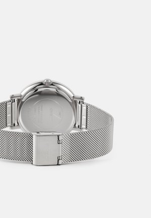 Sølvnetværks rem ur med et rund rustfrit stål urkasse, der har en glat bezel og en sikker lukkemekanisme. Bagsiden har brandgravering.