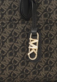 Borsa tote nera con accenti dorati e motivo logo impresso. Realizzata in materiale testurizzato con manico in pelle liscia.