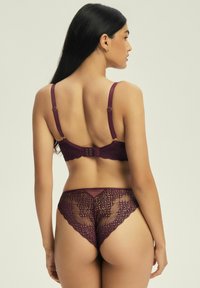 Burgundzka koronkowa biustonosz i pasujące majtki z misternym wzorem kwiatowym, przezroczystymi panelami, regulowanymi ramiączkami i zapięciem na haftkę.
