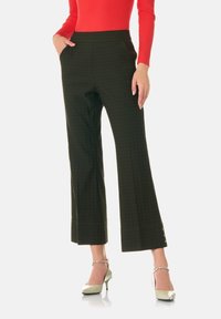 Mörkgrön rutiga vida byxor med en slät textur, sidfickor och splittat fåll, kombinerat med ljusgröna klackar.