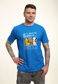 Modré bavlněné tričko s grafikou tří plyšových zvířátek a textem „Všechno, co chci na Vánoce... Sooty & Co,“ v slavnostním designu.