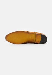 Suela de zapato de cuero en tono marrón, con forma afinada, textura suave y logotipo grabado. Tacón de goma duradero con ligero desgaste visible.