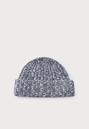Un bonnet en maille chinée bleu marine et blanc, avec un revers côtelé, présenté sur un fond clair uni.