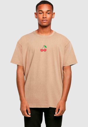 Beige Baumwoll-T-Shirt mit einem kleinen roten Kirschgrafik und einem grünen Blatt. Lockere Passform und kurze Ärmel. Maschinen genähte Details.