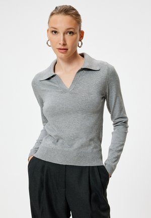 Grauer V-Ausschnitt Pullover mit kragenförmigem Halsauschnitt, aus weichem Strickstoff. Verfügt über lange Ärmel und einen gerippten Saum, kombiniert mit hochgeschnittenen schwarzen Hosen.