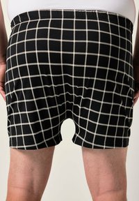 Boxer shorts neri con un motivo a griglia bianca, vita elastica e texture liscia, caratterizzati da una lunghezza a metà coscia e un design svasato.
