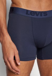 Marineblaue Levi's Boxershorts mit einem strukturierten Bund, der den Markennamen trägt. Glattes Material, enganliegendes Design, Länge bis zur Mitte des Oberschenkels.