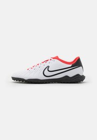 White athletic shoes with red accents, black sole, and textured upper featuring a wavy design. Prominent black Nike swoosh on the side.