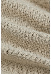 Tessuto a maglia beige chiaro con un motivo testurizzato, caratterizzato da un aspetto morbido e intrecciato e spessore del filo variabile in tutto il tessuto.