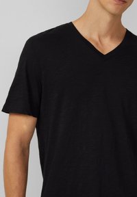 Czarny t-shirt z dekoltem w serek wykonany z lekkiego materiału, z krótkimi rękawami i luźnym krojem, charakteryzujący się gładką fakturą i minimalną ilością szwów.