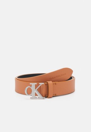 Jasnobrązowy pasek ze skóry z srebrną klamrą z logo "cK" Calvin Klein, zwinięty z widocznym tłoczeniem marki po wewnętrznej stronie.